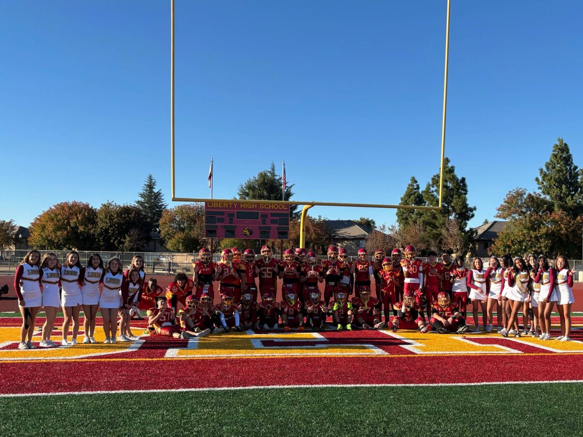 East County Lions football players and cheerleaders together in the end zone at Liberty High School
